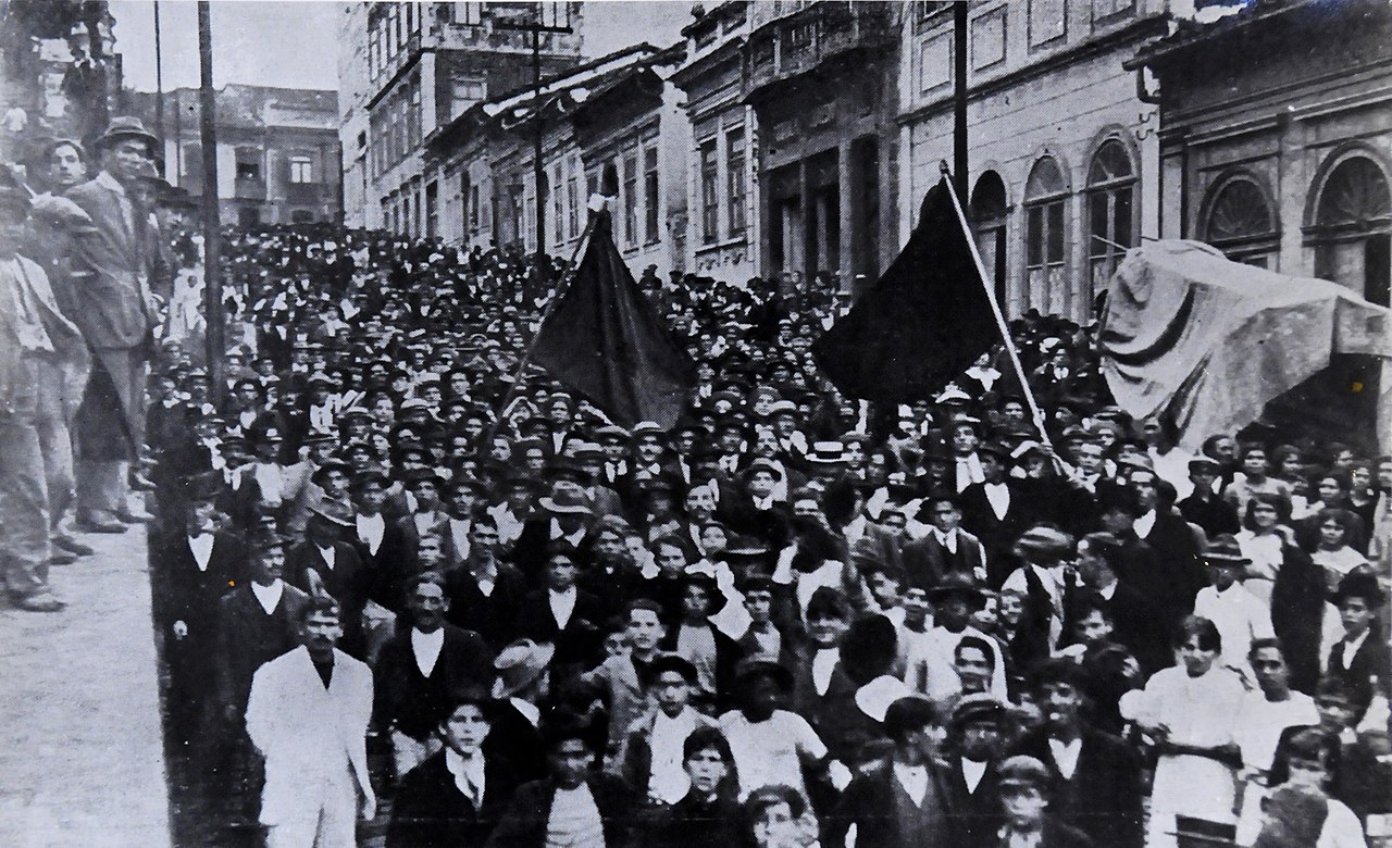 Thousands of workers line a wide street on a hill.